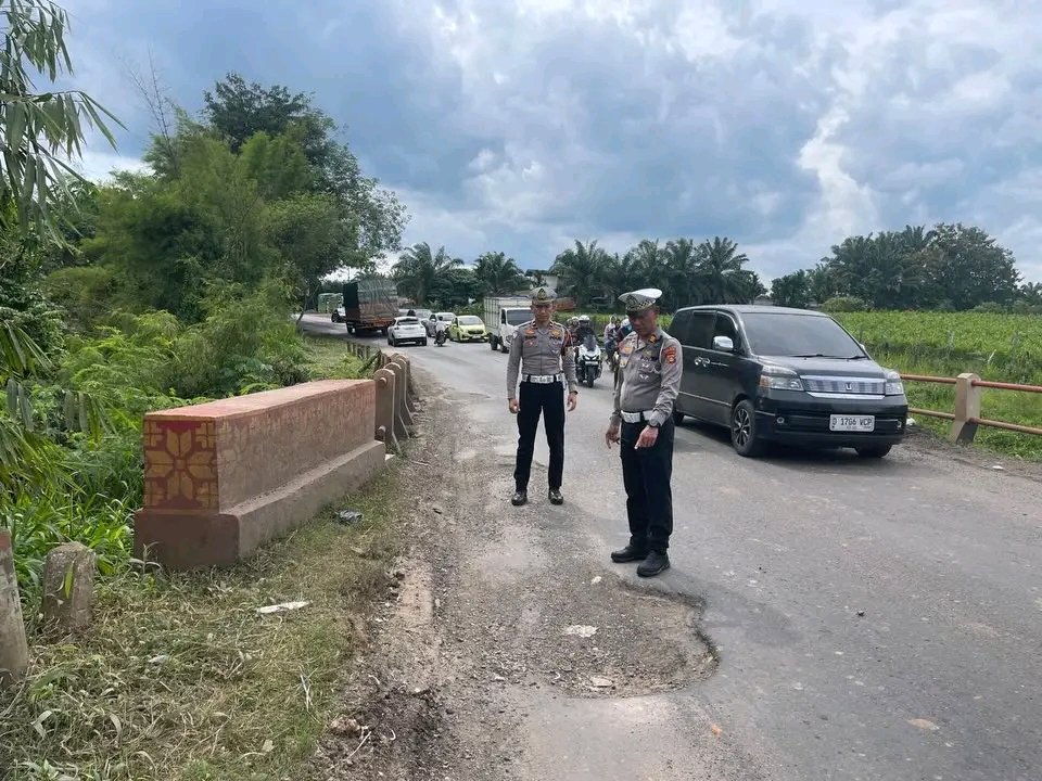 Dua personel Satlantas Polres Banyuasin mengecek titik jalan rusak dan berlubang di Jalintim KM 32–34 Banyuasin