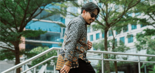 Pria mengenakan kemeja Batik Prabuseno dengan desain modern di area luar ruangan.
