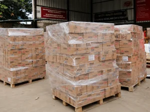 Tumpukan paket cargo yang telah dibungkus plastik dan disusun di atas pallet di area gudang